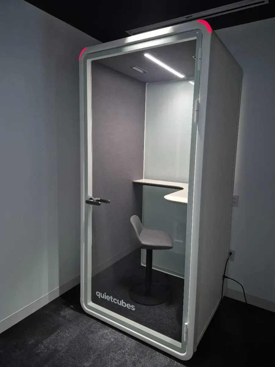Contact Us Minimalist soundproof phone booth with stool and desk inside a quiet office environment