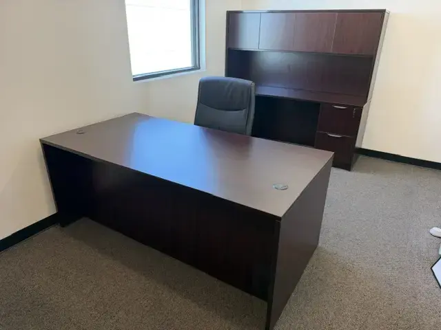 Contact Us Dark wood executive desk with black leather swivel chair and matching hutch in carpeted office