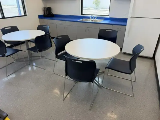 Contact Us Break room with round white tables, black chairs, blue countertop, sink, and white refrigerator