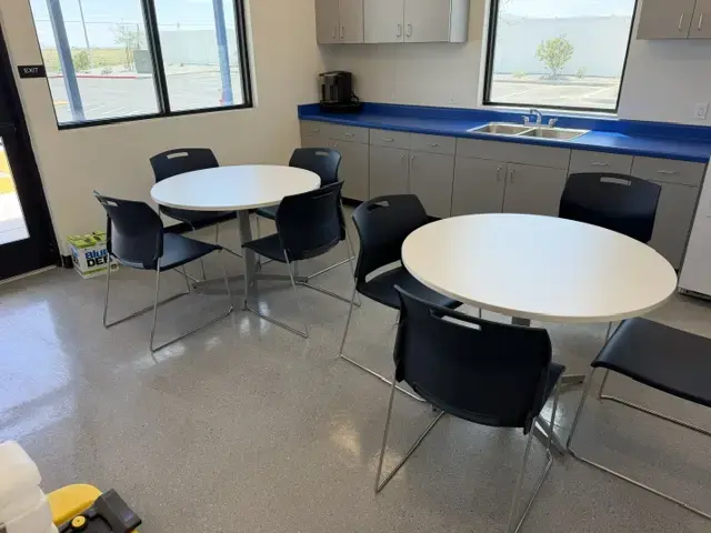 Contact Us Office break room featuring round white tables with black chairs, blue countertops, and windows for natural light