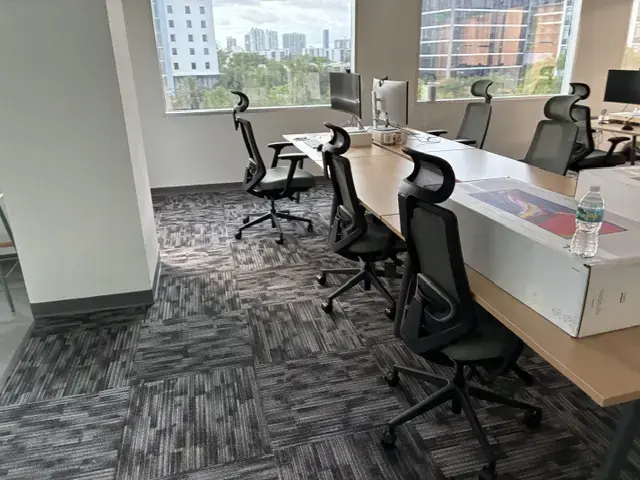 Creating a Finished Workplace in Miami Modern office workspace with ergonomic chairs, large desks, computers, and windows showing city buildings