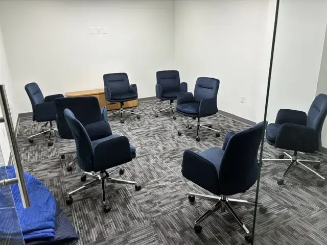 Creating a Finished Workplace in Miami Empty office meeting room with eight blue swivel chairs arranged in a circle on grey carpet flooring