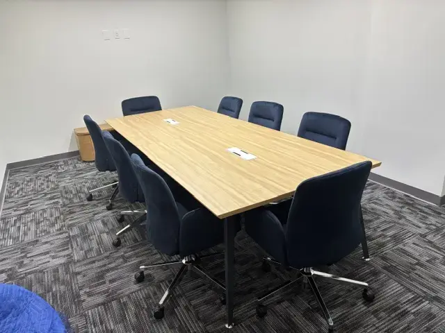 Creating a Finished Workplace in Miami Modern conference room with wooden rectangular table surrounded by eight blue office chairs on carpeted floor