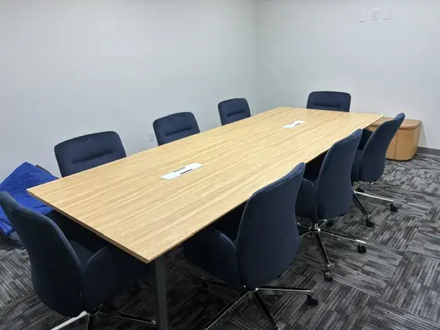Creating a Finished Workplace in Miami Modern conference room with wooden rectangular table surrounded by eight blue office chairs on carpeted floor