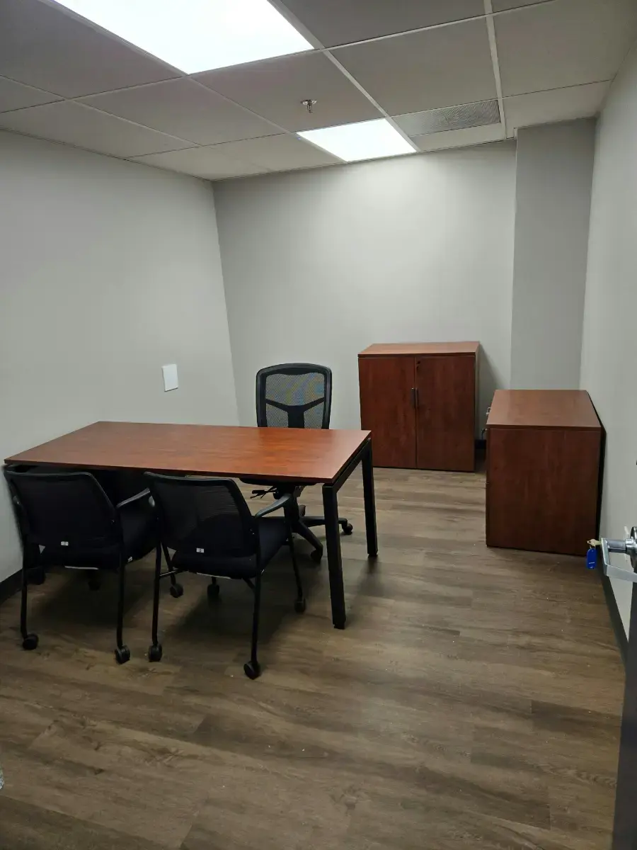 Let Us Help Build Your Next Workspace Small office meeting room with a wooden table, three chairs, and two storage cabinets