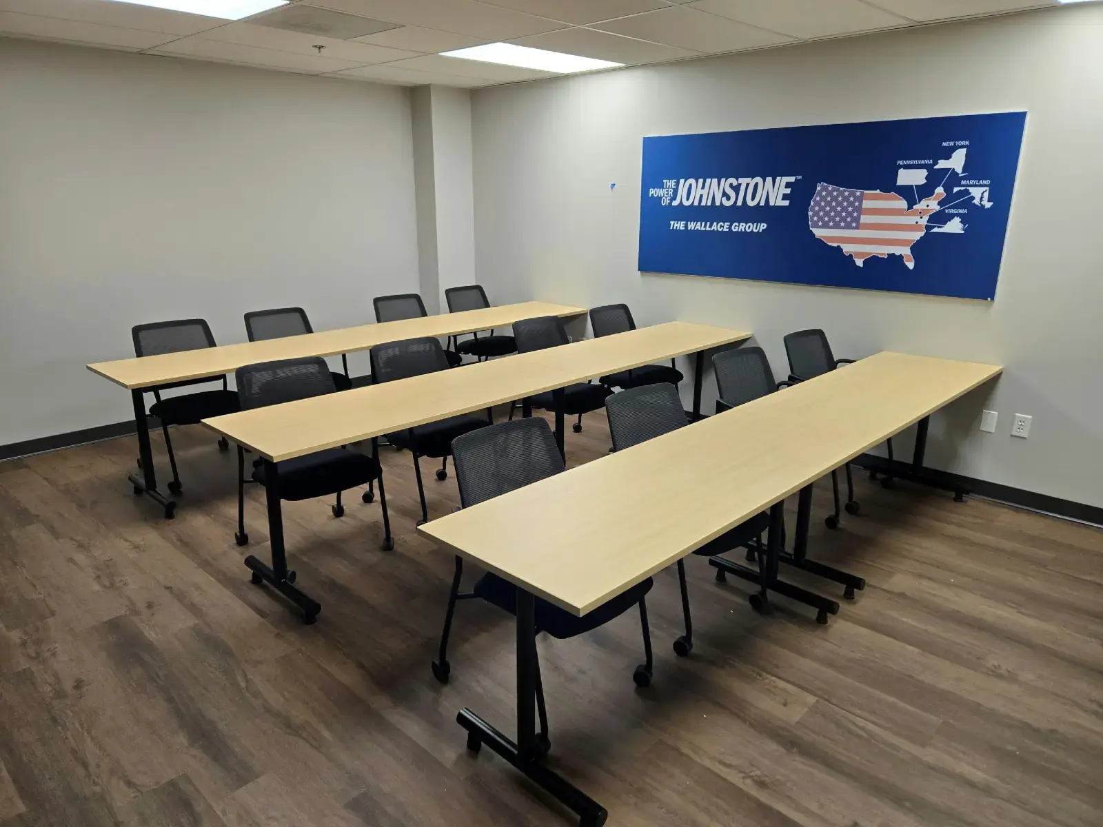 Let Us Help Build Your Next Workspace Empty Johnstone Wallace Group training room with rows of tables and chairs beneath a branded U.S. map
