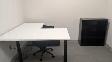 Kansas City, MO: Primary Care Office Furniture Installation Creates a Professional Patient Environment L-shaped white desk, office chair, and black bookshelf in a small office
