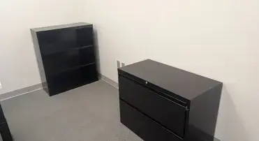 Kansas City, MO: Primary Care Office Furniture Installation Creates a Professional Patient Environment Black bookshelf and two-drawer filing cabinet in an office