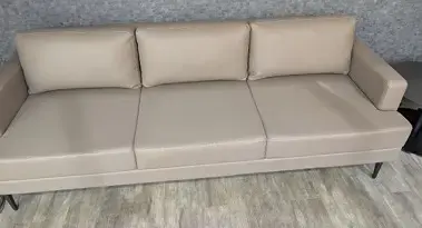 Kansas City, MO: Primary Care Office Furniture Installation Creates a Professional Patient Environment Beige three-seat sofa against a textured gray wall